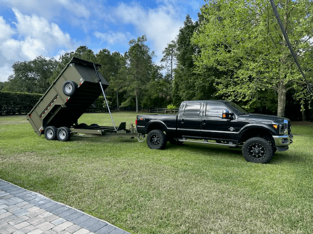 A black dump truck unloading debris into a dumpster.